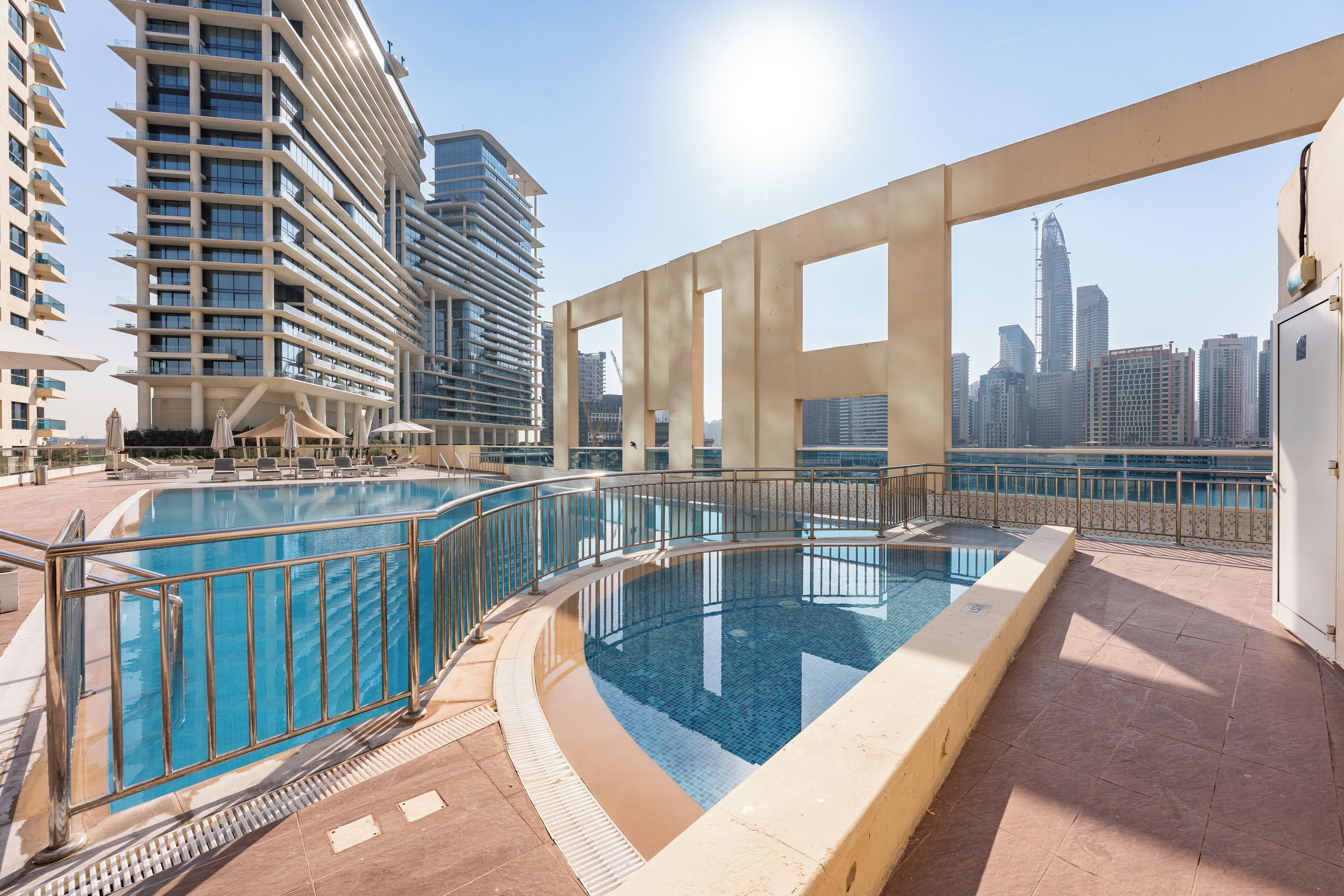 A rooftop swimming pool with a city skyline in the background.