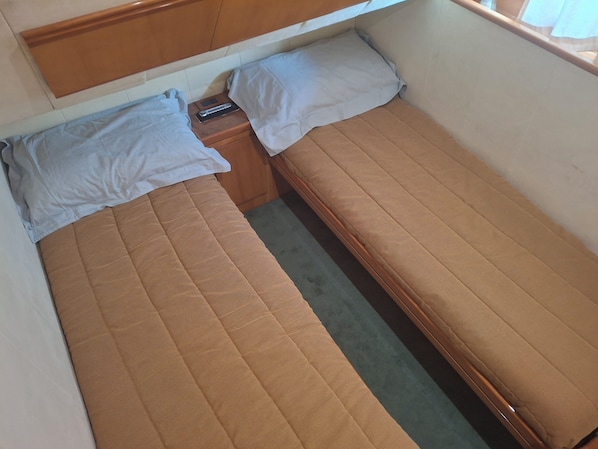A small, single-bed room with a wooden headboard, a bedside table, and a pillow.