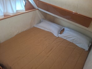 A small, single-bed room with a wooden headboard and a window with curtains.