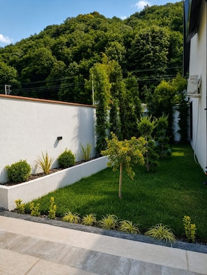 A landscaped garden with a white wall, various shrubs, and a small tree. - NOW ANGEL' BUNGALOW (Sapanca)
