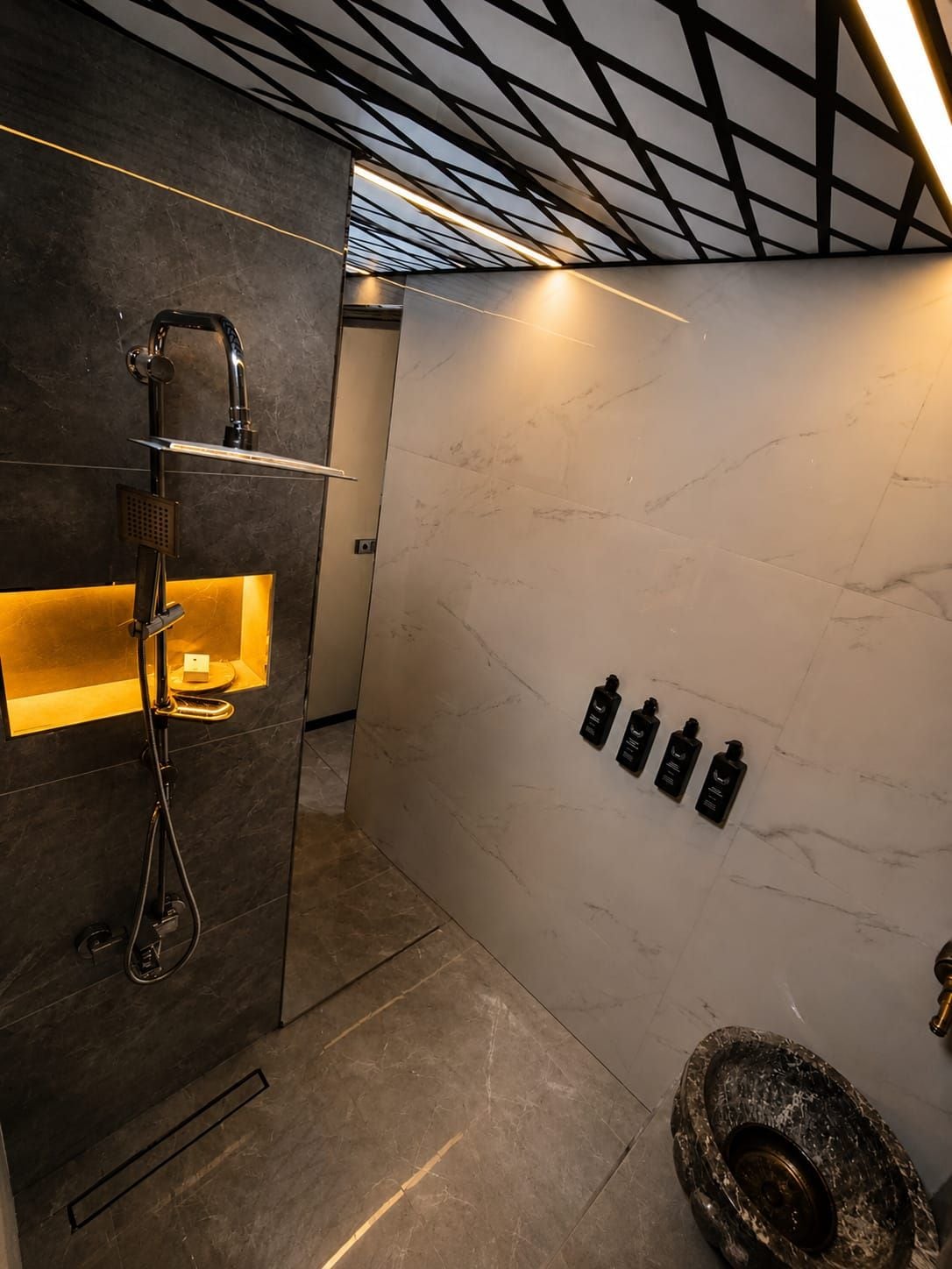 Un baño moderno con ducha integrada, paredes de mármol y un diseño de inodoro original.