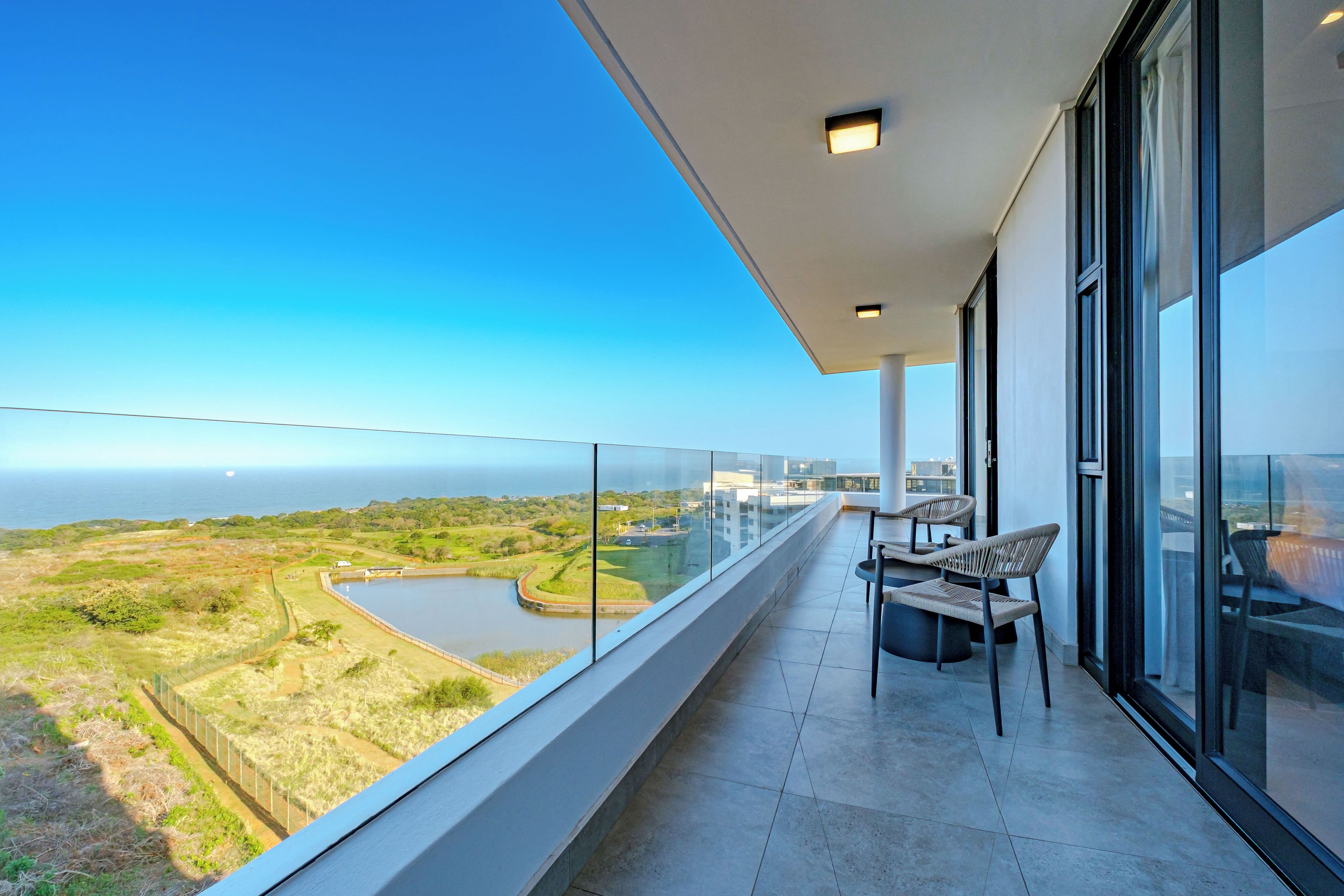 A balcony with a view of a body of water and greenery.