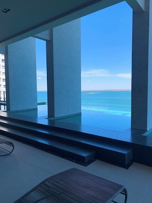 Un área de piscina interior moderna con vista al océano.