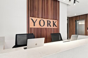 A reception desk with a 'YORK' sign, two black chairs, and a laptop on the counter. - Panoramic Ocean-View 3BR York Penthouse (Umhlanga)