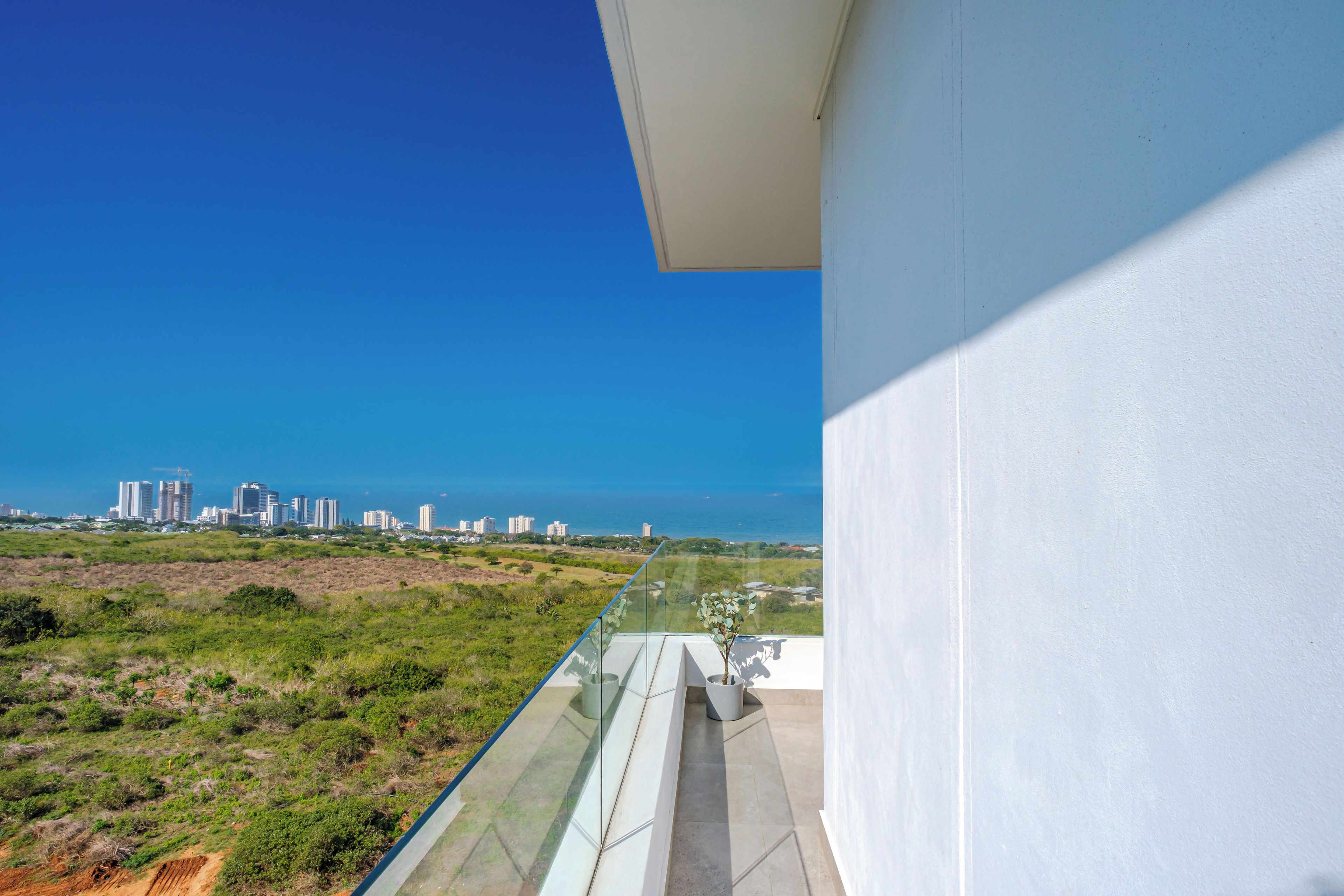 A balcony with a clear view of a city skyline and the ocean.