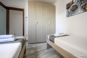 Een slaapkamer met twee bedden, een garderobe en een kunstwerk aan de muur.