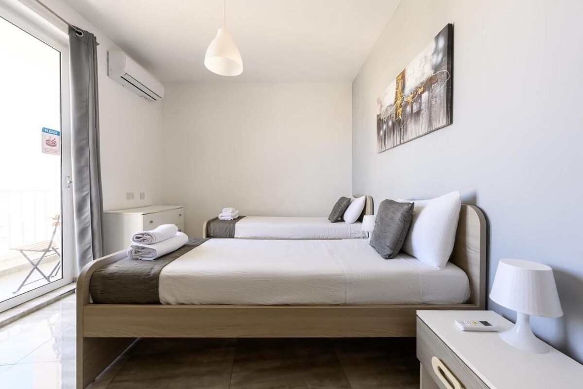 Ein Hotelzimmer mit zwei Betten, einem Nachttisch, einer Lampe und einem Bild an der Wand.