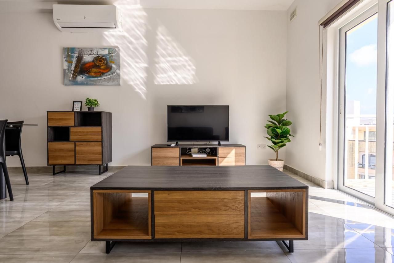 Un soggiorno moderno con una TV a schermo piatto, arredi in legno e una grande finestra con vista sulla città.