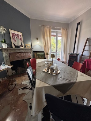 Uma sala de jantar com mesa posta para quatro pessoas, lareira e vista para o exterior.