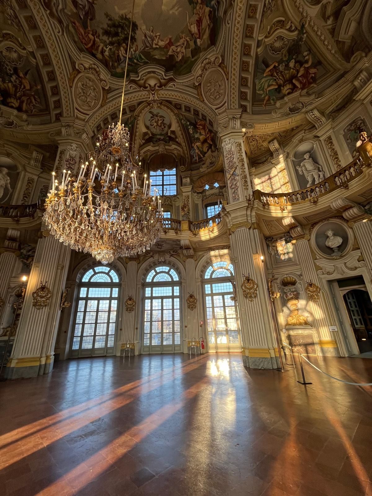Ein prachtvoller Saal mit einem großen Chandelier, Bogenfenstern und aufwendigen Deckenverzierungen.