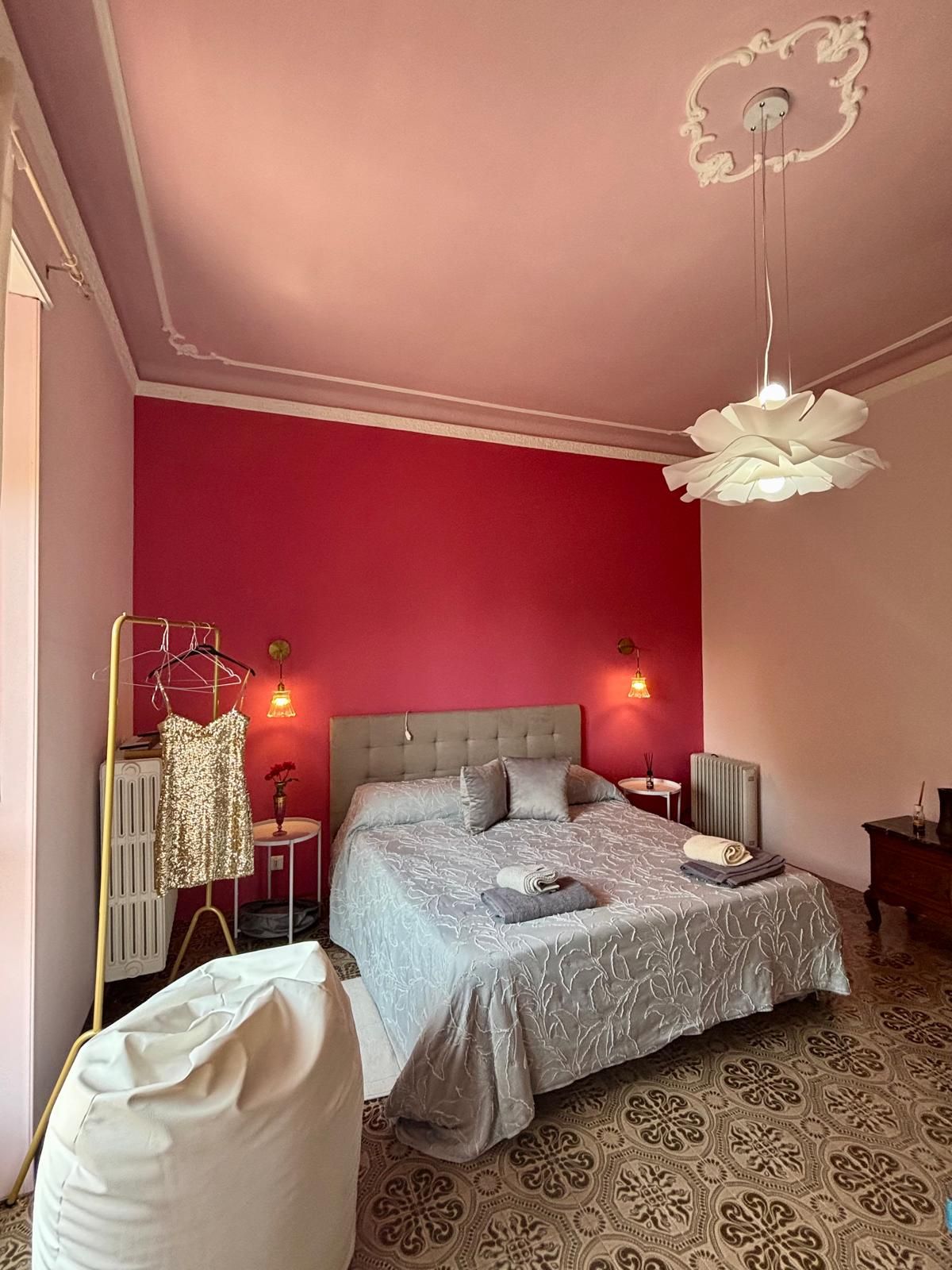 Une chambre à coucher avec un grand lit, deux tables de chevet, un luminaire suspendu et un radiateur.