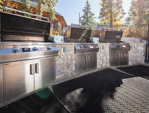 Eine gewerbliche Grillstation im Freien mit mehreren Kochflächen und einer Wand aus Stein im Hintergrund.