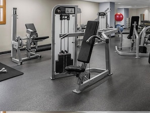 Ein Fitnessstudio mit unterschiedlichen Trainingsgeräten, darunter Kraftmaschinen und Kurzhanteln.