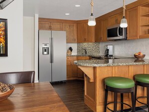 Una cocina con gabinetes de madera, un refrigerador de acero inoxidable, un microondas y una encimera de granito.