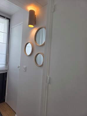 A hallway with a door, a light fixture, and three wall-mounted mirrors.