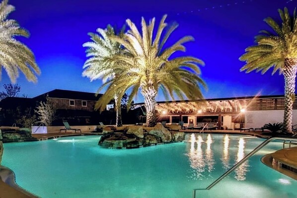 A swimming pool with palm trees and a building in the background.