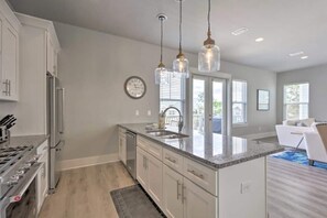 A modern kitchen with a central island, stainless steel appliances, and pendant lighting.