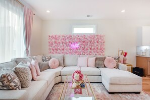 A living room with a sectional sofa, a glass coffee table, and a floral wall decoration. - NEW HOUSE Nash Bash Babes 2 BED/2BATH - Sleeps 10 (Nashville)