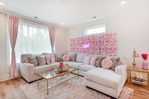 Ein Wohnzimmer mit einer Eckcouch, einem Couchtisch und einer Wand, die mit rosa Blumen dekoriert ist.
