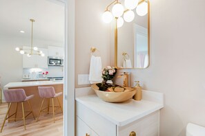 Ein modernes Badezimmer mit einem großen Spiegel, goldenen Armaturen und einem weißen Waschbecken.