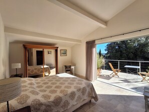 Ein Schlafzimmer mit einem großen Bett, einem Schreibtisch und einem Balkon mit Stühlen und einem Tisch.