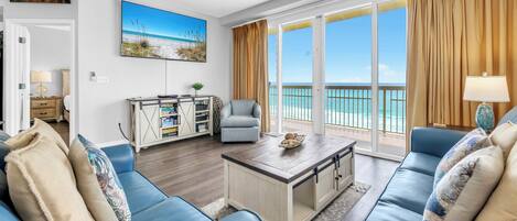 Ein Wohnzimmer mit einer Couch, einem Couchtisch, einem Fernseher und Blick aufs Meer.