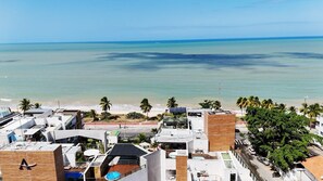 A coastal urban area with buildings, a beach, and palm trees. - Acqualina Resort By Day by Day (JOÃO PESSOA)