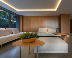A modern living room with a sofa, a coffee table, and a plant. - Acqualina Resort By Day by Day (JOÃO PESSOA)