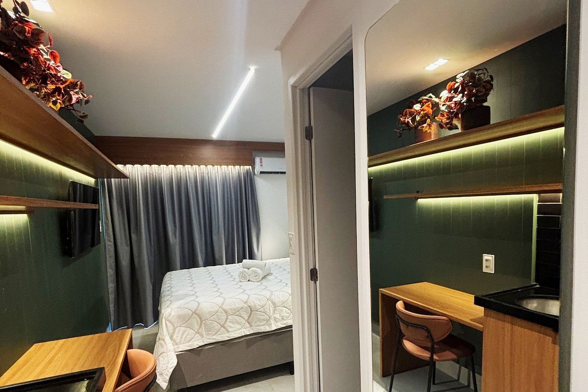 Pieni hotellihuone, jossa on sänky, työpöytä, tuoli ja peili.