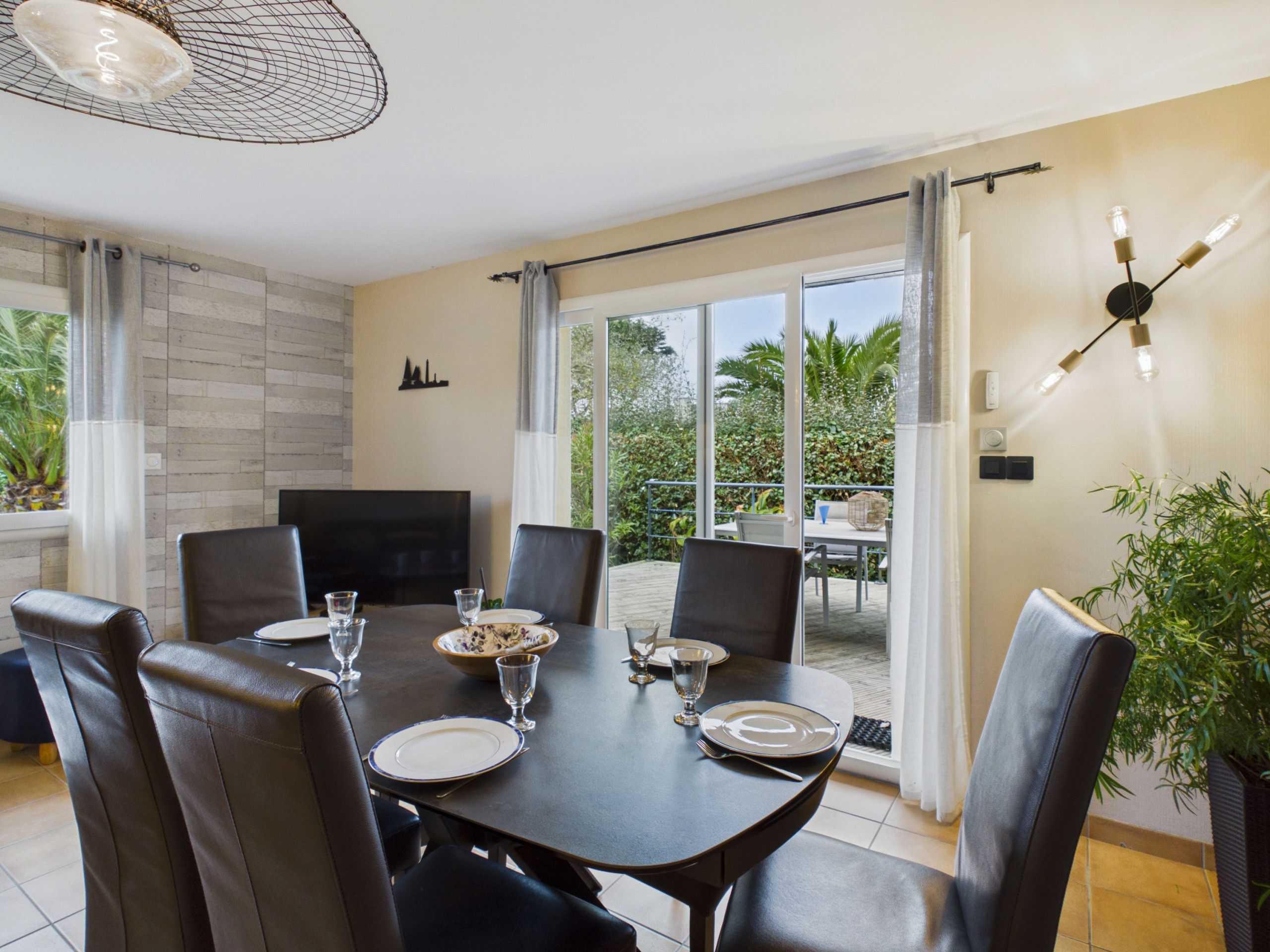 Un coin repas avec une table dressée pour quatre personnes, un téléviseur à écran plat et une vue sur l’extérieur.