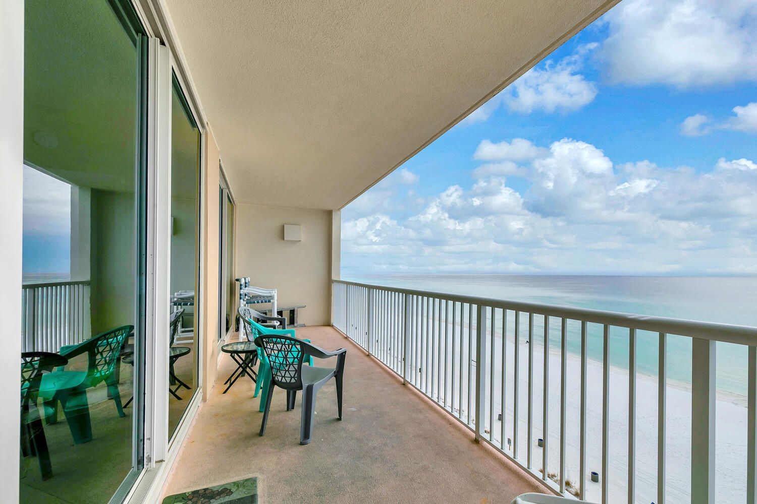 A balcony with a view of the ocean, a table with chairs, and a railing.