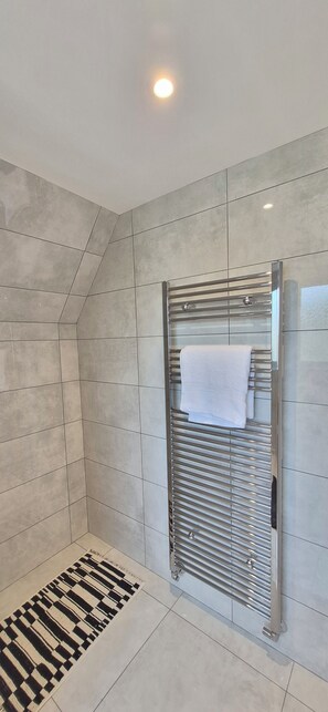 Ein modernes Badezimmer mit Dusche, gefliesten Wänden und einem strukturierten Boden.