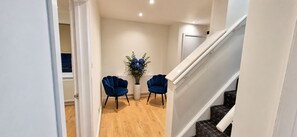 A hallway with a staircase, two blue chairs, and a potted plant with blue flowers. - NEW I 3 BEDROOM HOUSE I DUDLEY I WEST MIDLANDS I POOL TABLE I FAMILY (Dudley)