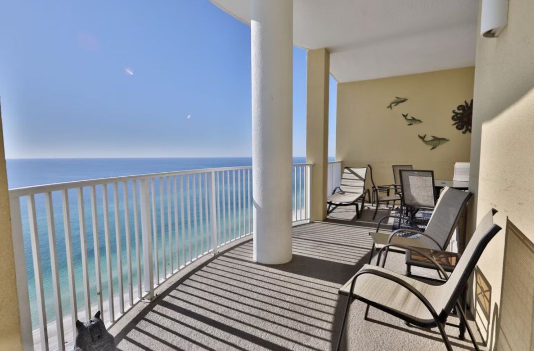 A balcony with a view of the ocean, white columns, and a wall with dolphin decorations.