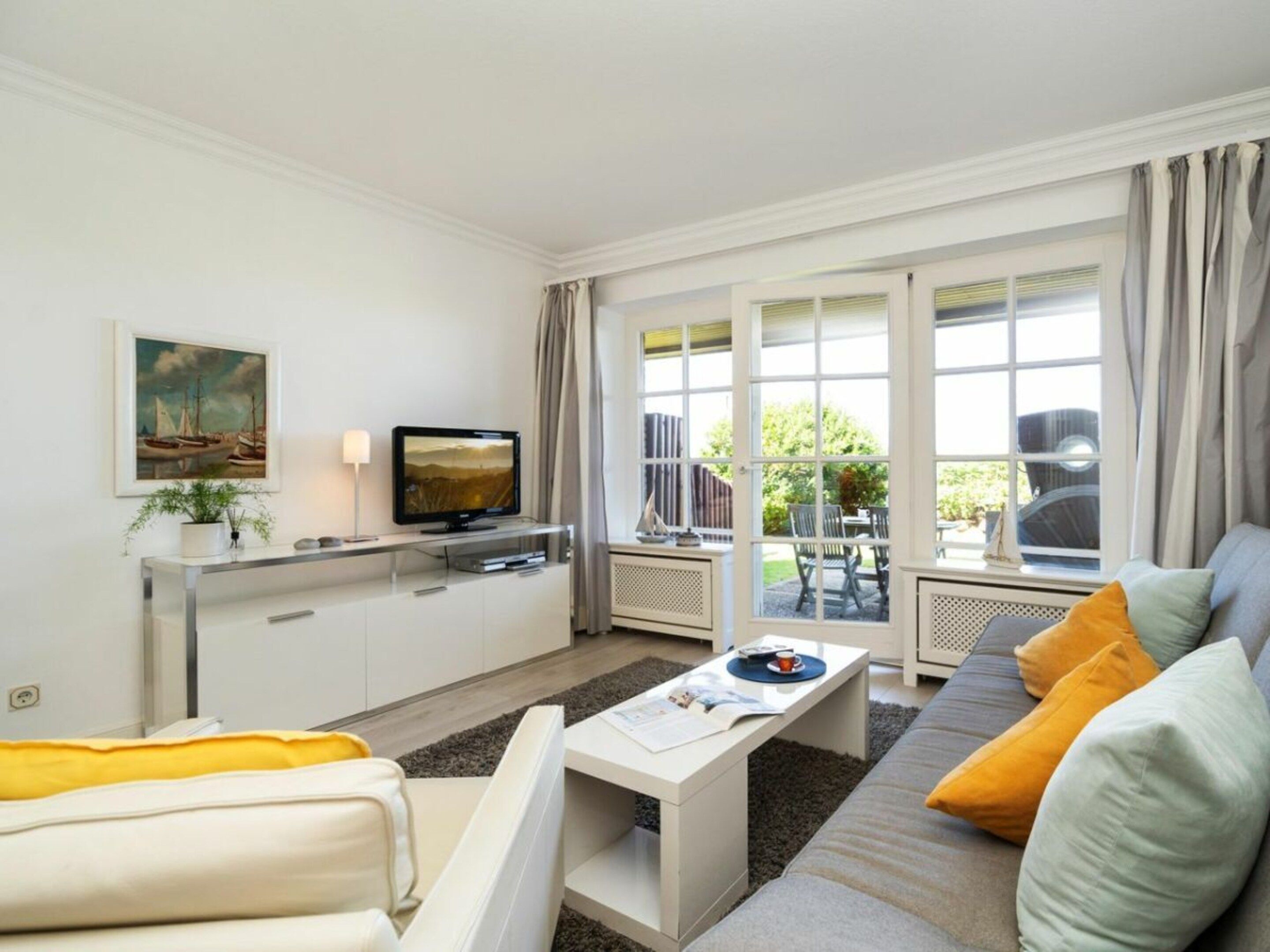 A modern living room with a sofa, a coffee table, a TV, and a dining area with chairs and a table.