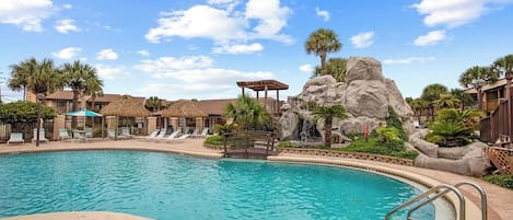 A swimming pool with lounge chairs and a rock formation.