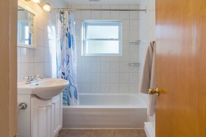 Ein Badezimmer mit einem weißen Waschbecken, einer Badewanne und einer Duschvorhang.