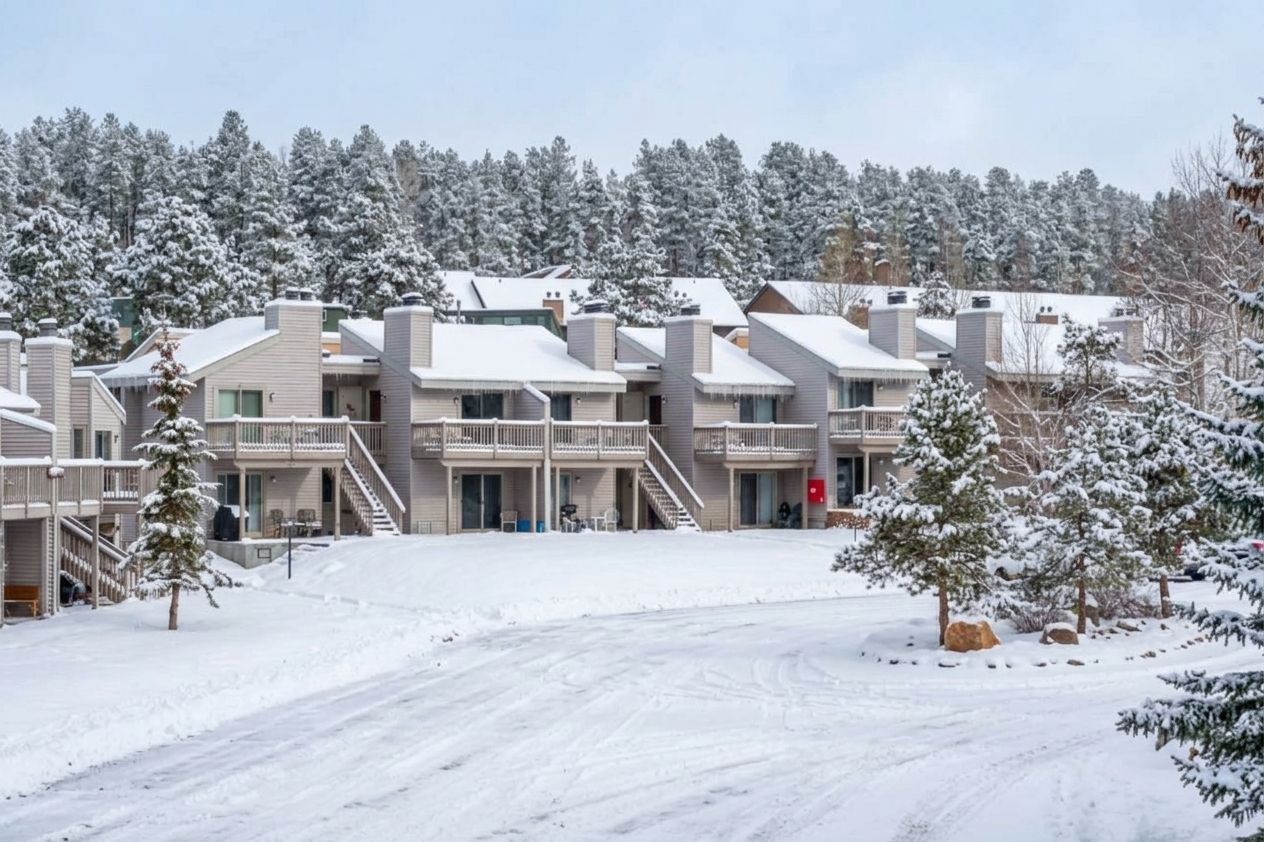A multi-story building with balconies, a covered walkway, and a snowy landscape.