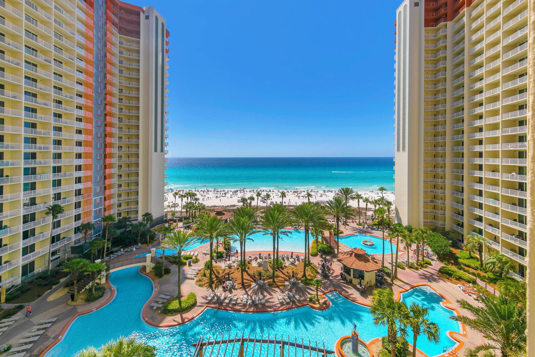 A hotel with a pool area, beach view, and multiple balconies.