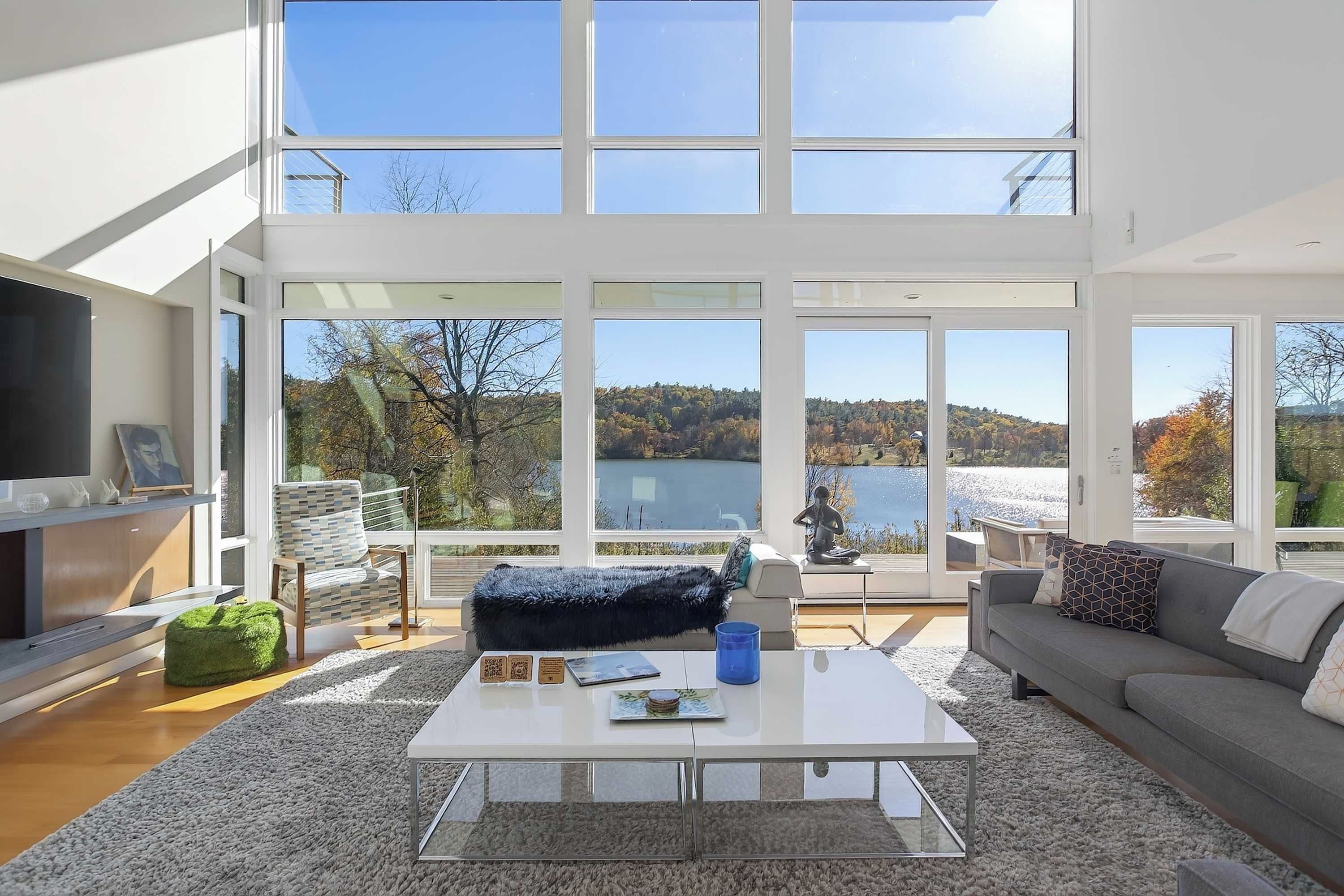 A modern living room with a large window, a sofa, a coffee table, and a television.