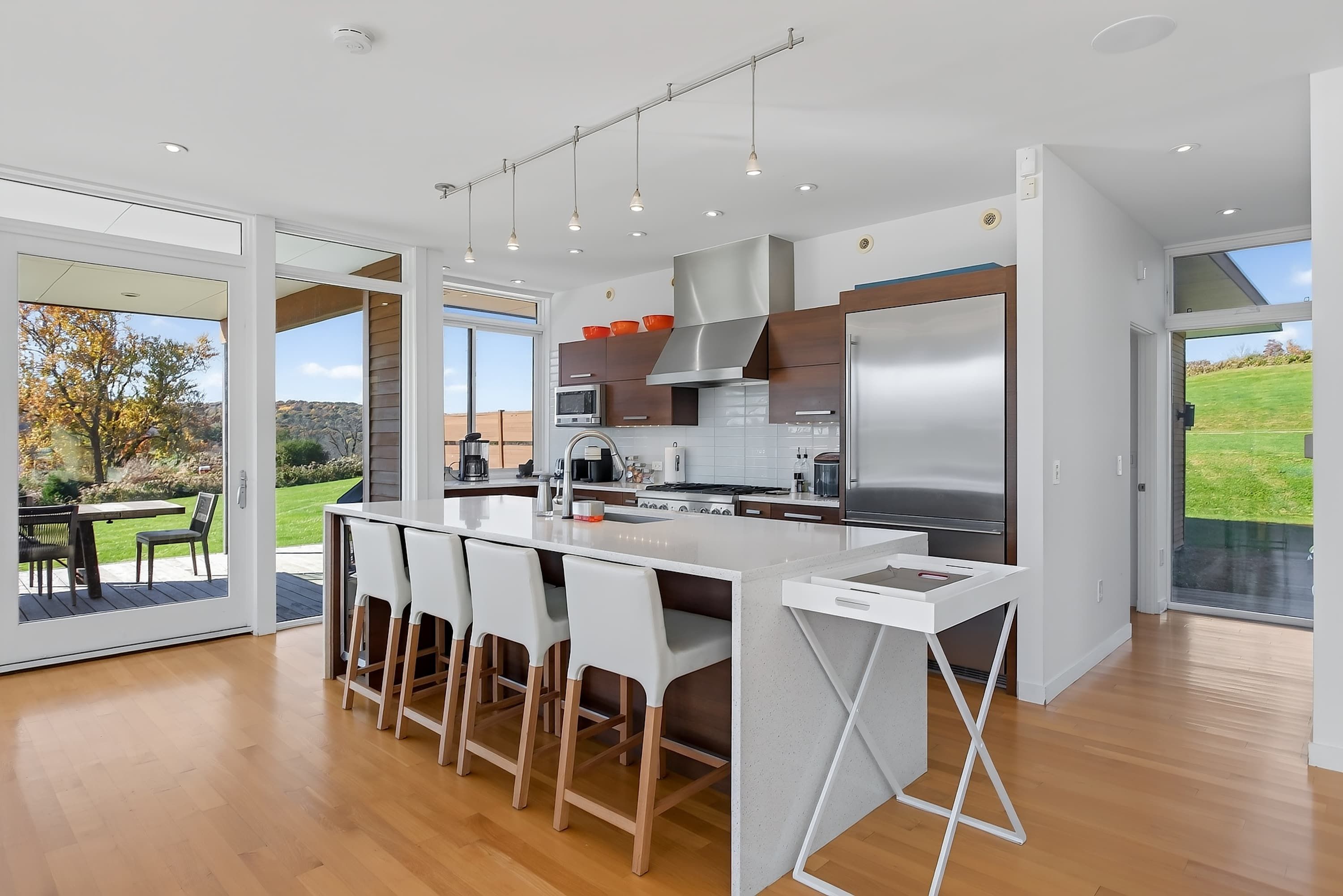 A modern kitchen with a central island, stainless steel appliances, and a view of a garden.