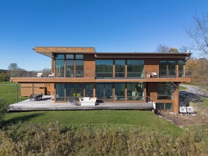 A modern two-story house with large windows and a deck. - Hillsdale Lakeside | Modern Lakefront Retreat (Hillsdale)