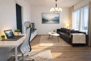 En moderne stue med et skrivebord, en sofa, et sofabord og et billede på væggen.