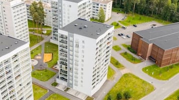 Un edifici residencial de grans alçades, amb múltiples balcons, una zona d'aparcament i un camp esportiu.