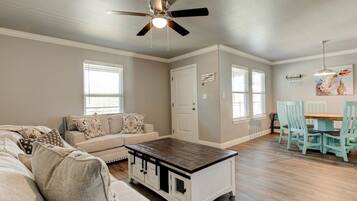 A living room with a sofa, coffee table, and dining area with chairs.