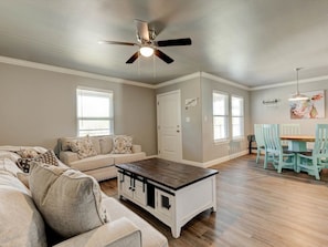 A living room with a sofa, coffee table, and dining area with chairs. - Cozy 2 Bedroom Apartment in Historic Granbury (Granbury)