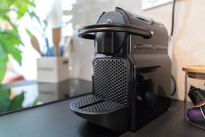 Máquina de café com bandeja coletora de água e painel de controle.