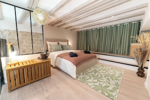 A modern bedroom with a large bed, a wooden bedside table, a mirror, and a view of the outdoors. - New Listing (Nice)
