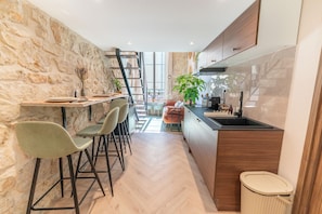 Uma cozinha moderna com parede de pedra, armários de madeira e padrão de piso em padrão herringbone.