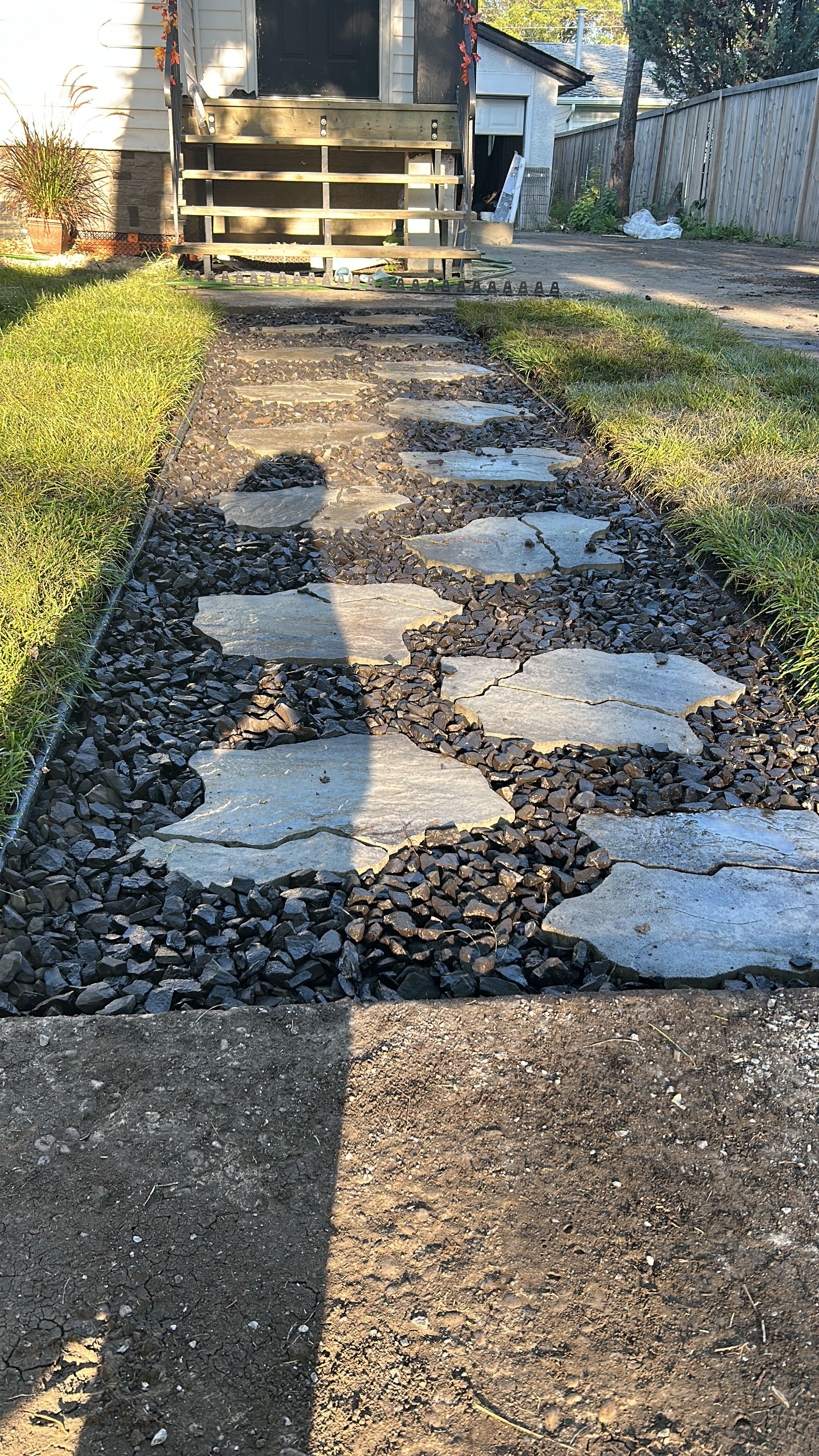 Un sendero con piedras y grava que conduce a una terraza de madera.